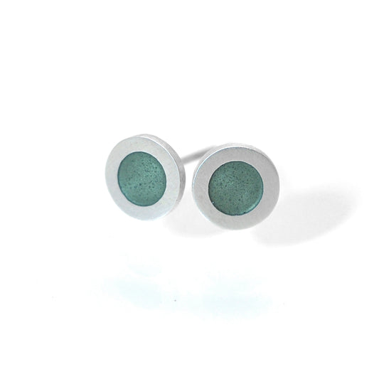 Small flat round ear studs with green grey coloured enamel in the centre