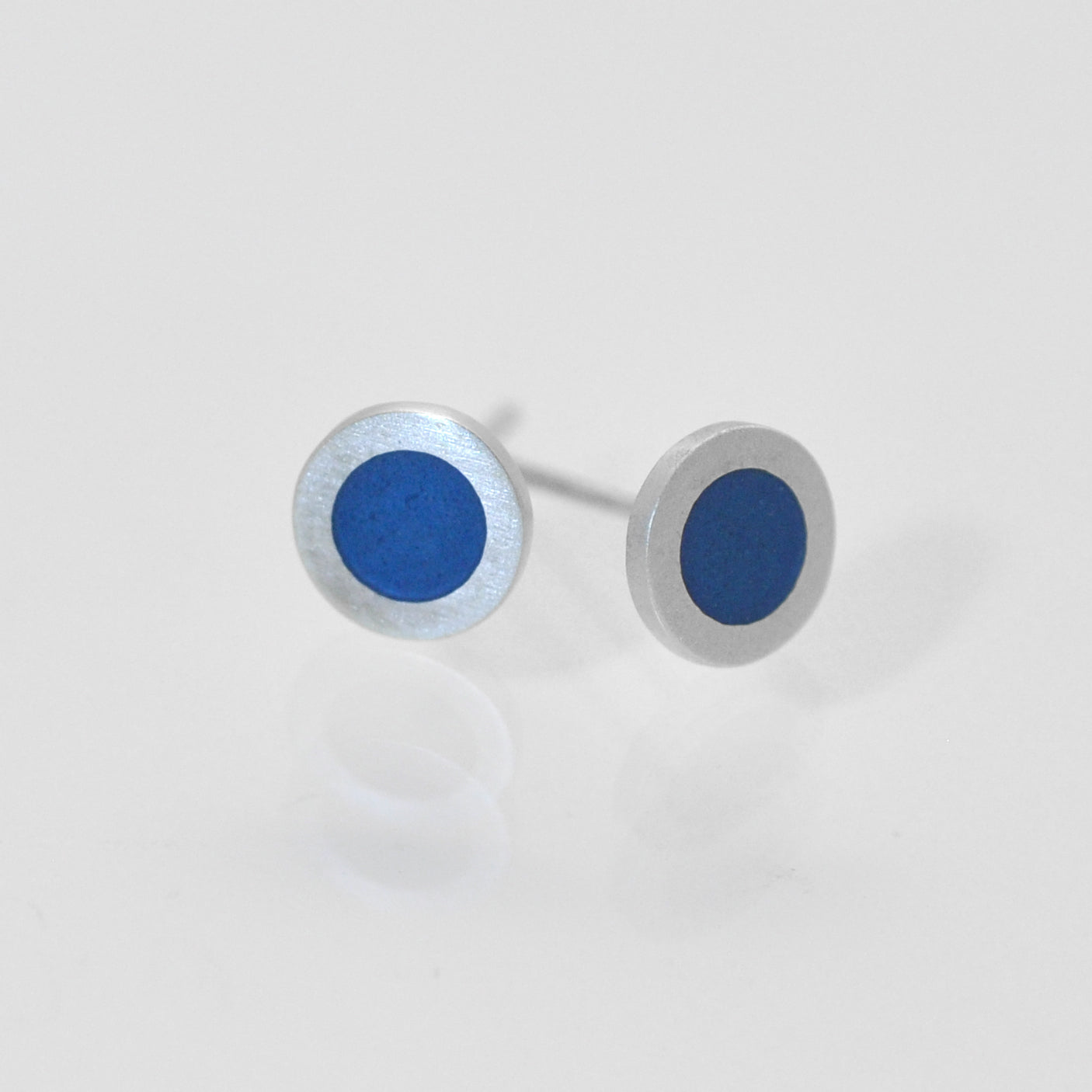 Small flat round ear studs with mid grey- bluecoloured enamel in the centre