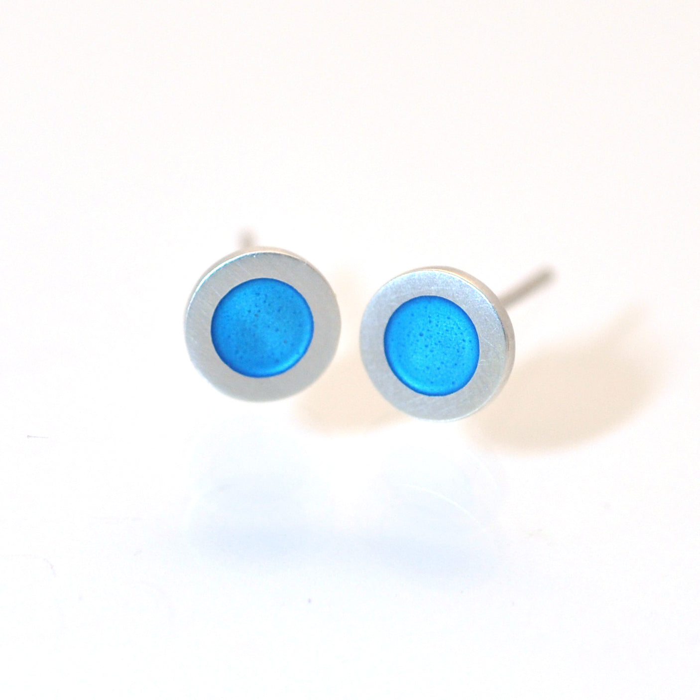 Small flat round ear studs with blue turquoise coloured enamel in the centre